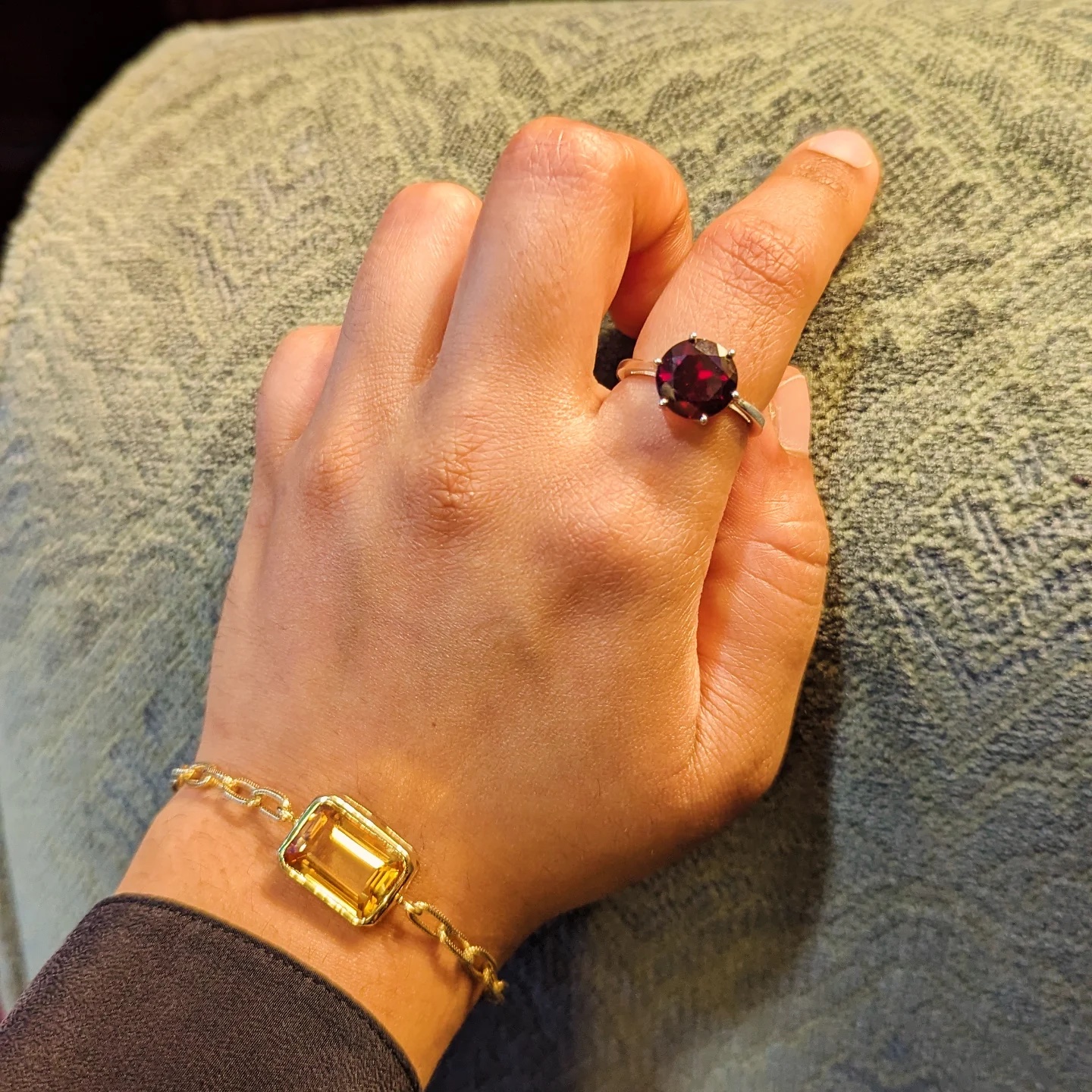 Garnet ring worn with a citrine bracelet in warm indoor light.
